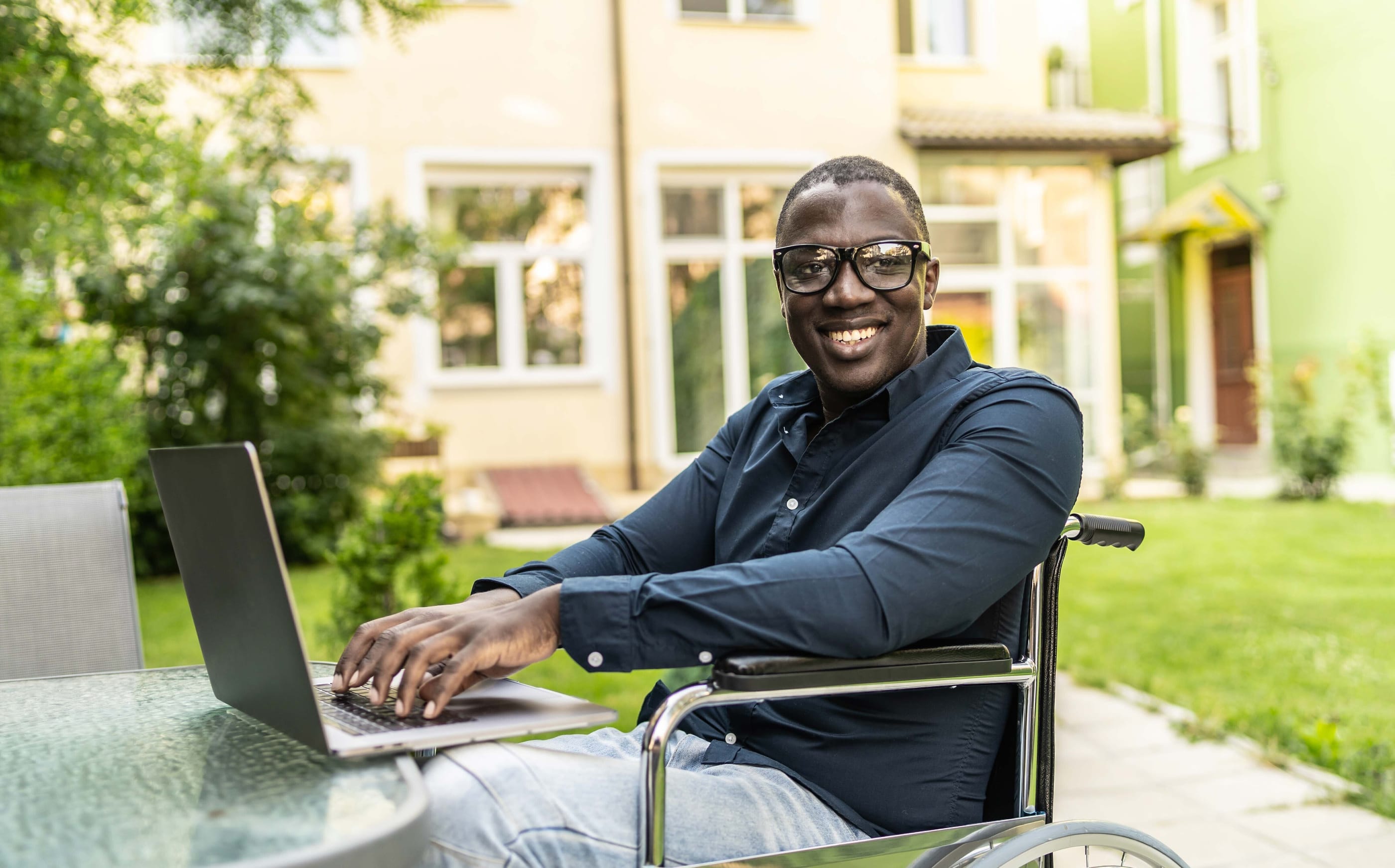 Man in wheelchair using a laptop outside