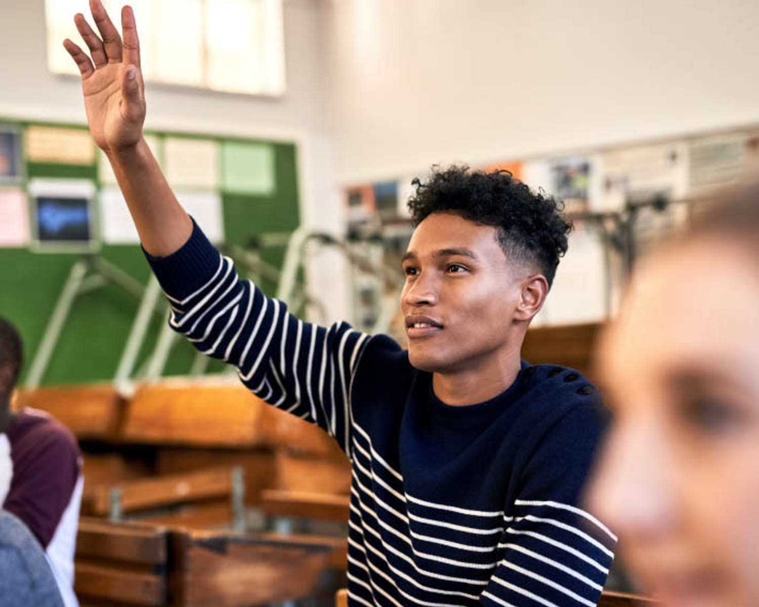 Un estudiante afroamericano levanta la mano en un aula