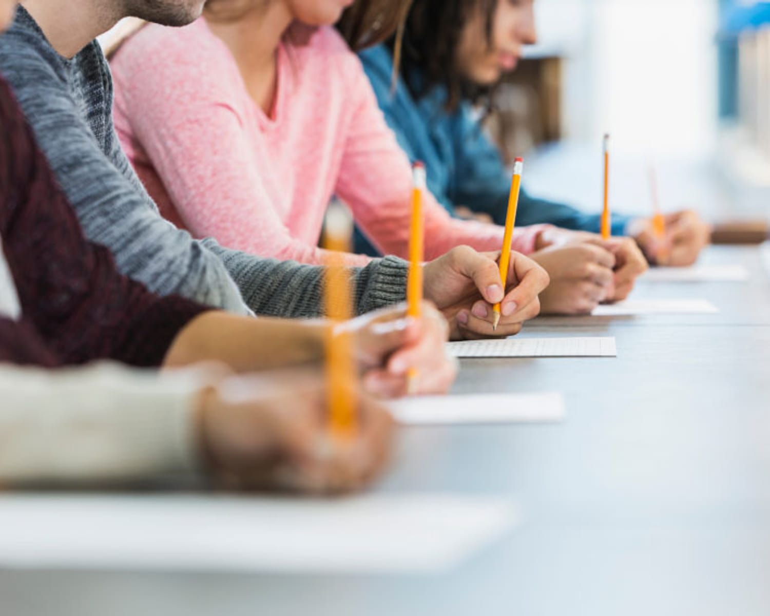 Primer plano de los estudiantes usando lápices en papel durante la clase